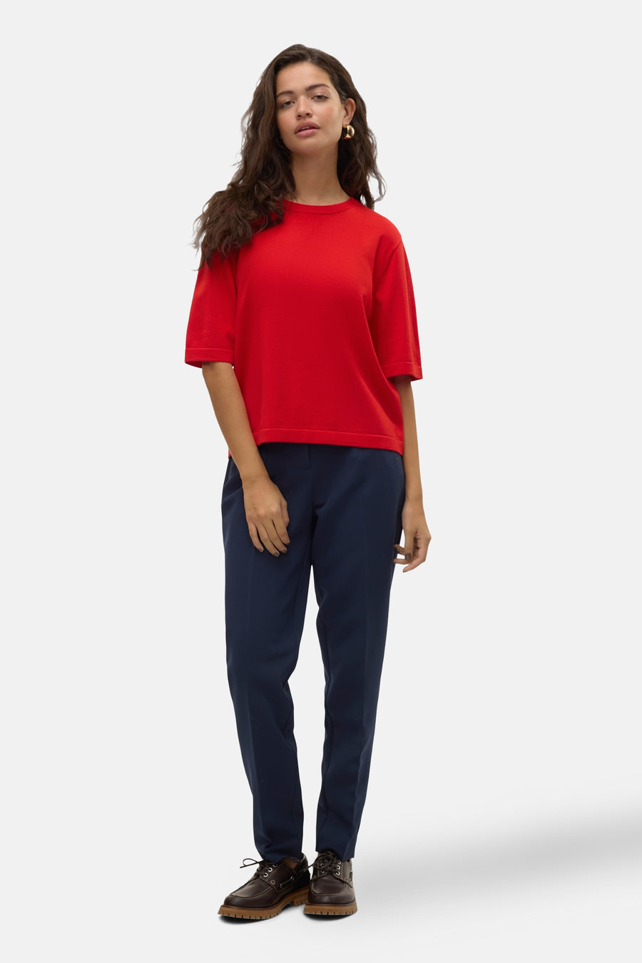 Rode trui met ronde hals van VERO MODA®, gedragen met een donkerblauwe pantalon en bruine schoenen.
