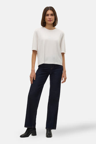 Witte trui met ronde hals van VERO MODA®, gecombineerd met donkere jeans en zwarte laarsjes.