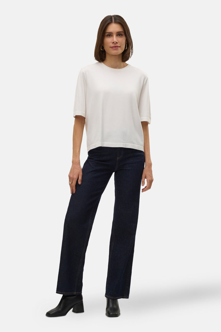 Witte trui met ronde hals van VERO MODA®, gecombineerd met donkere jeans en zwarte laarsjes.
