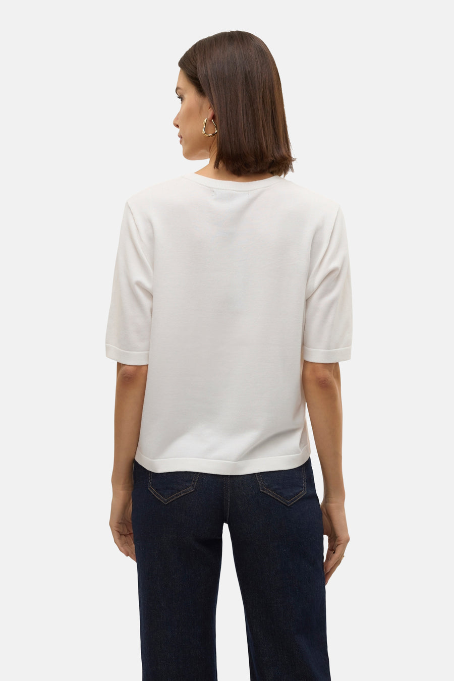 Witte trui met ronde hals van VERO MODA®, gezien van achteren, gecombineerd met donkerblauwe jeans en gouden oorbellen.