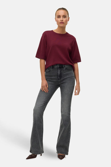 Bordeaux trui met ronde hals van VERO MODA, gedragen met grijze jeans en bruine hakken met versiering.