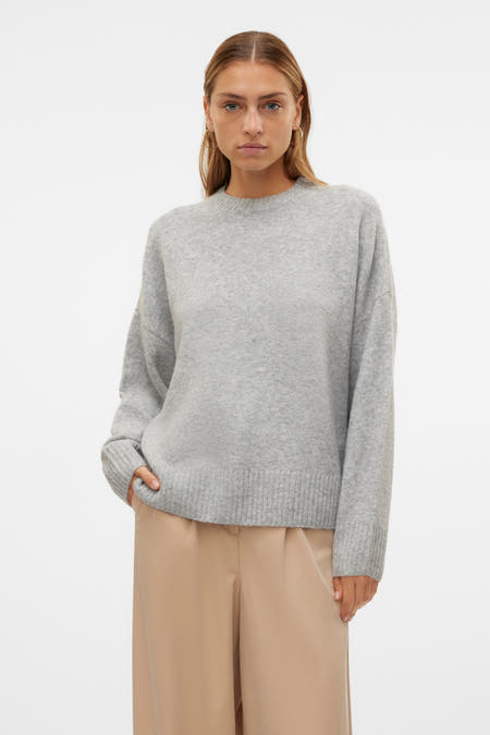 Grijze trui met ronde hals van Vero Moda, gedragen met beige broek en gouden oorbellen.
