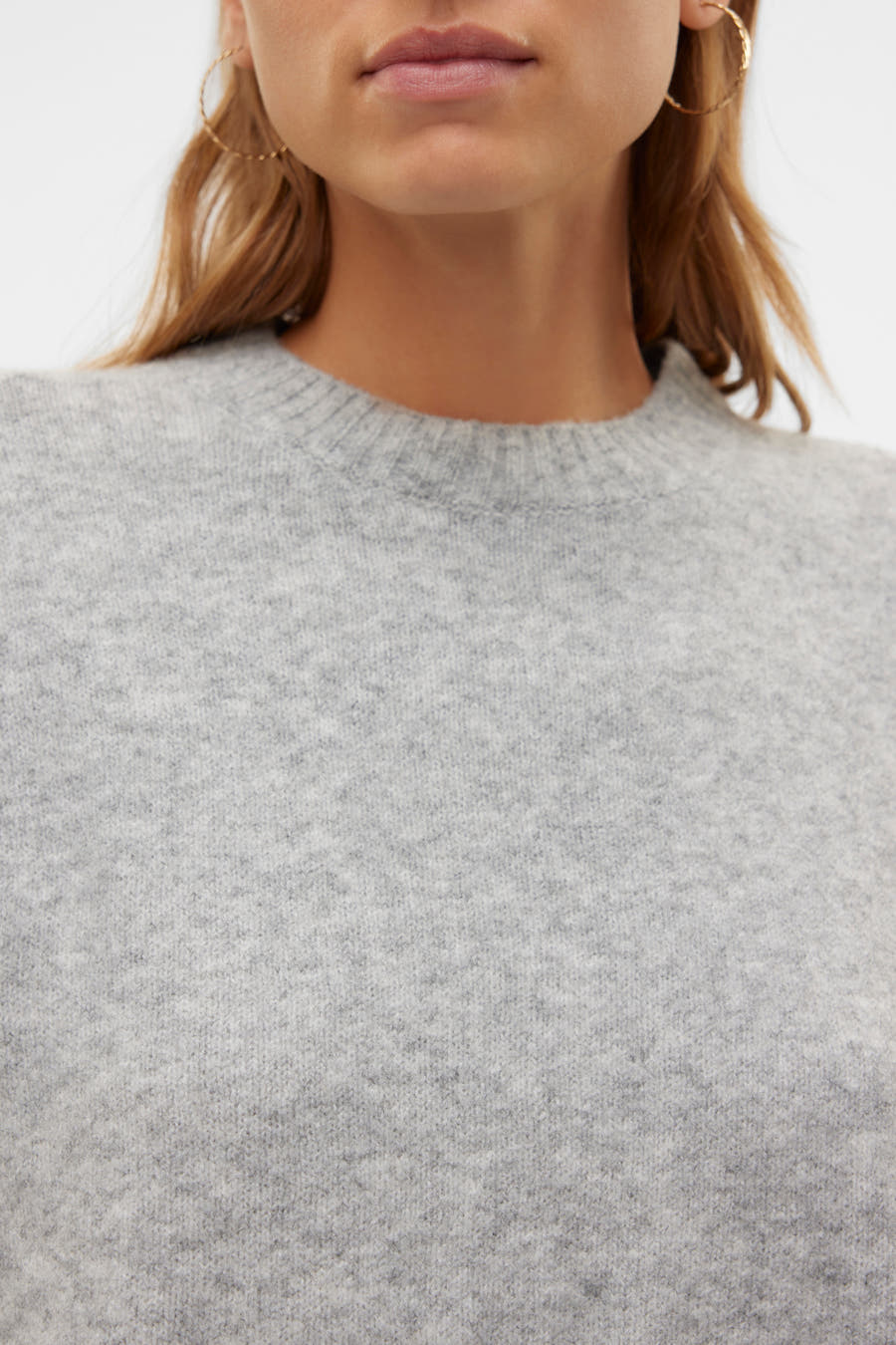Grijze trui met ronde hals van VERO MODA, getoond met gouden oorbellen.