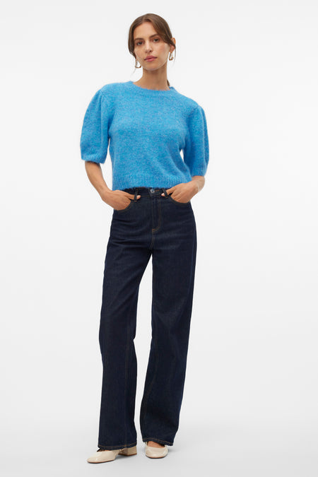 Blauw ronde hals trui van VERO MODA®, met pofmouwen, gecombineerd met donkere jeans en crèmekleurige schoenen.
