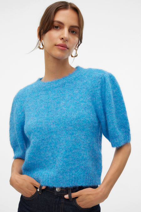 Blauwe trui met ronde hals van VERO MODA, met korte mouwen, gedragen met een donkere jeans en gouden oorbellen.
