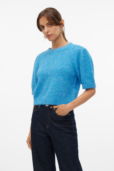 Blauwe trui met ronde hals van VERO MODA, gecombineerd met donkere jeans en gouden oorbellen.