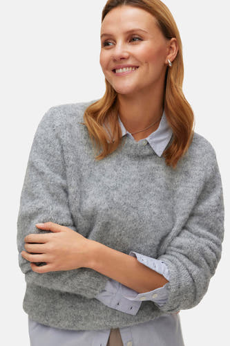 Grijze ronde hals trui van Vero Moda, met lange mouwen over een lichtblauw overhemd heen.
