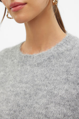 Grijze trui met ronde hals van VERO MODA, met zachte textuur en details van gouden oorbellen.
