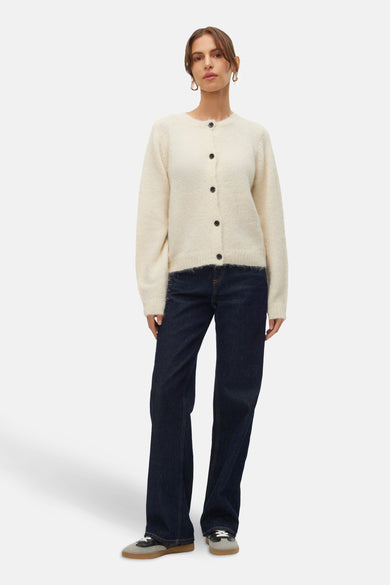 Ecru cardigan van VERO MODA®, met lange mouwen, knoopsluiting en gedragen met donkere jeans en sneakers.
