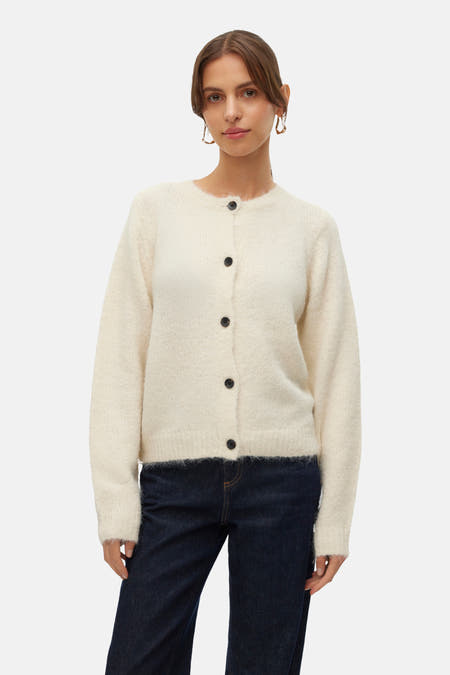 Ecru vest van VERO MODA®, met lange mouwen, zwarte knopen en gedragen met een donkere jeans.
