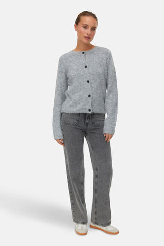 Grijze cardigan van Vero Moda, met lange mouwen, zwarte knopen en gecombineerd met grijze jeans.
