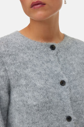 Grijze cardigan van VERO MODA, met knoopsluiting en een zachte textuur, gedragen met zilveren oorbellen.
