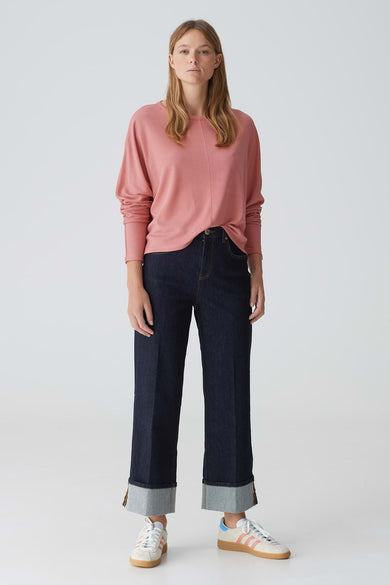 Roze trui met ronde hals van OPUS, met lange mouwen, gecombineerd met donkere jeans en witte sneakers.
