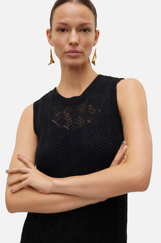 Robe sans manches noire de VERO MODA avec un motif tissé ouvert et des boucles d'oreilles dorées.
