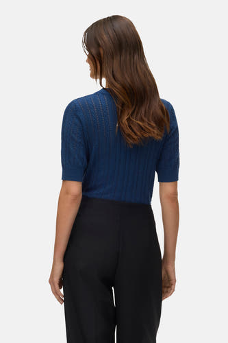 Blauwe trui met ronde hals van Vero Moda, met ajourpatroon en korte mouwen, gecombineerd met een zwarte broek.