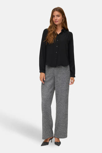 Grijze broek van VERO MODA®, gecombineerd met een zwarte blouse en zwart-witte hakken.