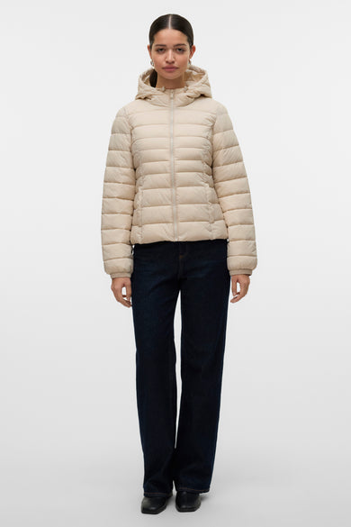 Korte ecru jas van VERO MODA, met capuchon, gecombineerd met een donkerblauwe jeans en zwarte schoenen.
