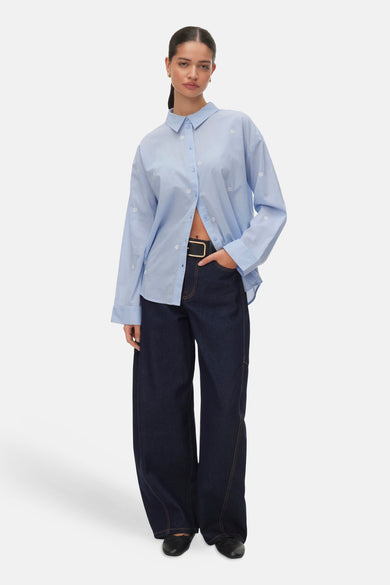 Blauw overhemd met lange mouwen van VERO MODA® met bloemenpatroon, gecombineerd met wijde, donkere jeans en zwarte schoenen.
