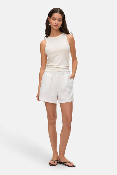 Witte korte broek van VERO MODA, gecombineerd met een mouwloze top en sandalen, staand op een witte achtergrond.
