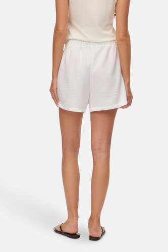 Witte short van VERO MODA, gezien van achteren, met een elastische tailleband en sandalen.

