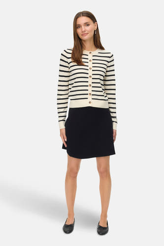 Zwarte korte rok van Vero Moda, gecombineerd met een gestreept gebreid vest en zwarte ballerina's.

