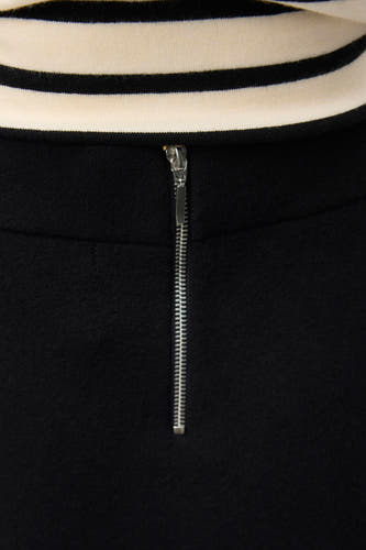 Zwarte korte rok van VERO MODA, met een zilverkleurige ritssluiting aan de achterkant en een gestreepte top.
