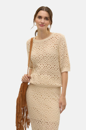 Gilet beige avec col rond de VERO MODA, tricoté avec une structure ouverte, associé à une longue jupe et un sac marron frangé.