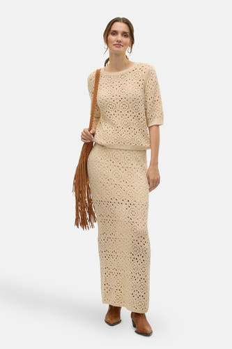 Beige trui met ronde hals van VERO MODA, gehaakt met open structuur, gecombineerd met een lange rok en bruine tas met franjes.
