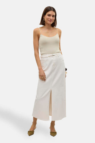 Long manteau blanc de VERO MODA, avec une fente à l'avant, associé à un top spaghetti et des talons bas.