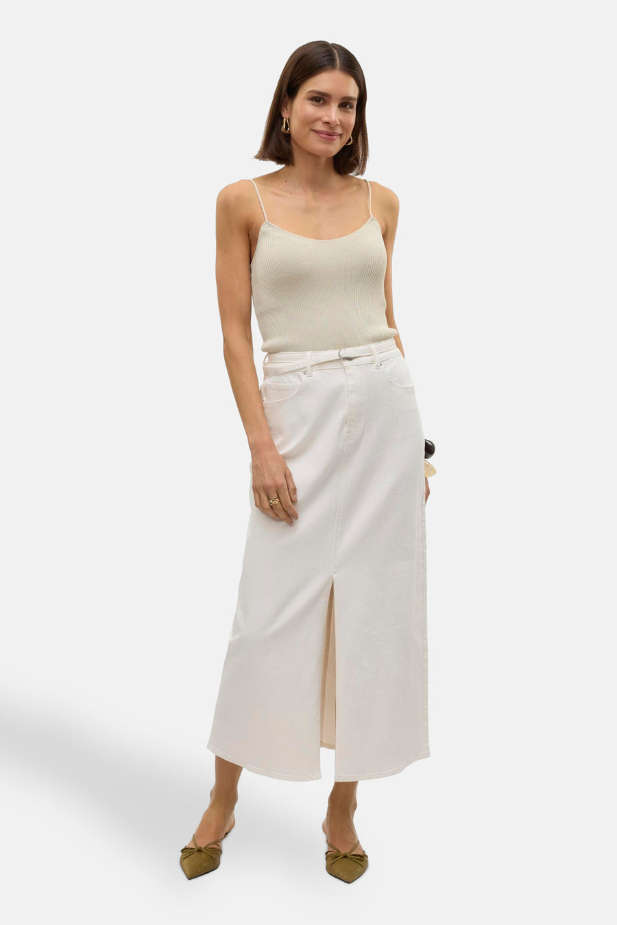 Long manteau blanc de VERO MODA, avec une fente à l'avant, associé à un top spaghetti et des talons bas.