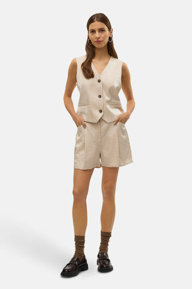 Ecrukleurige short van VERO MODA, gecombineerd met een bijpassend gilet, bruine sokken en zwarte loafers.