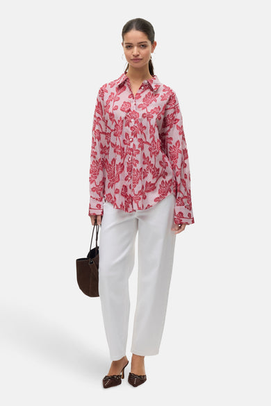 T-shirt rayé rouge de Vero Moda avec des manches longues, à imprimé floral, porté avec un pantalon blanc et des baskets brunes.