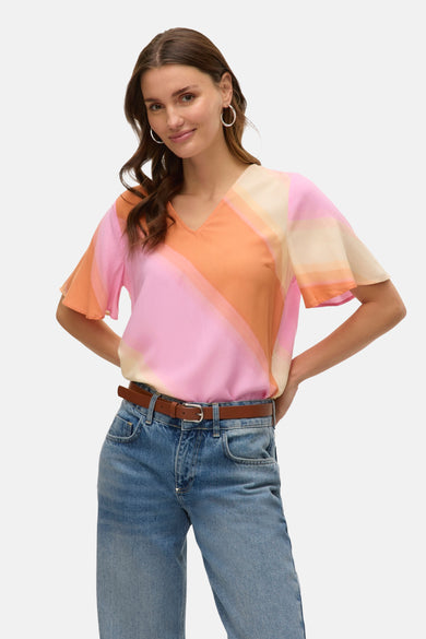 Multikleurige blouse van VERO MODA met diagonale kleurvlakken, gedragen met een bruine riem en jeans.
