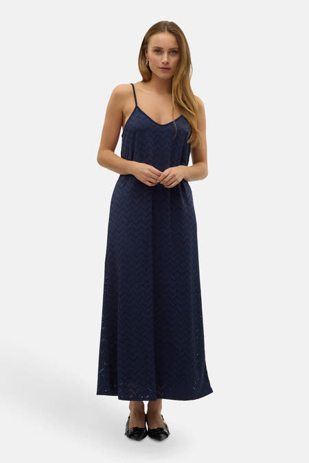 Robe bleue marine sans manches de VERO MODA®, avec un motif zigzag perforé, portée avec des escarpins noirs.