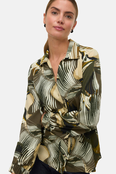 Groen hemd met lange mouwen van VERO MODA, met bladmotief en zwarte oorbellen.