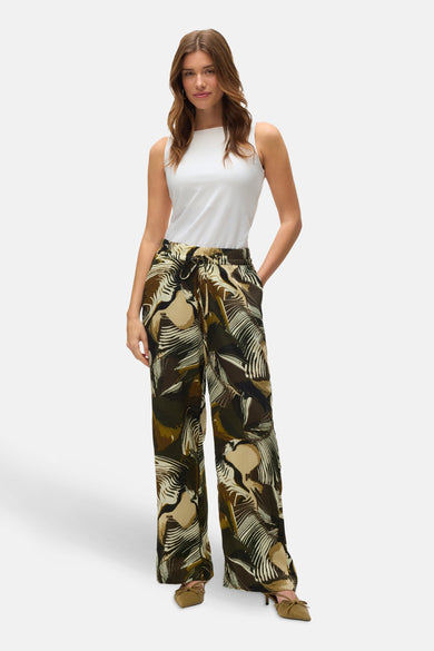 Pantalon vert de VERO MODA® avec un motif feuille et une ceinture à la, associé à une chemise blanche et des chaussures marrons.