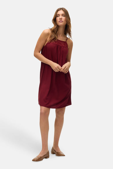 Bordeaux kleedje zonder mouwen van Vero Moda, met kanten details aan de halslijn, gedragen met bruine schoenen.
