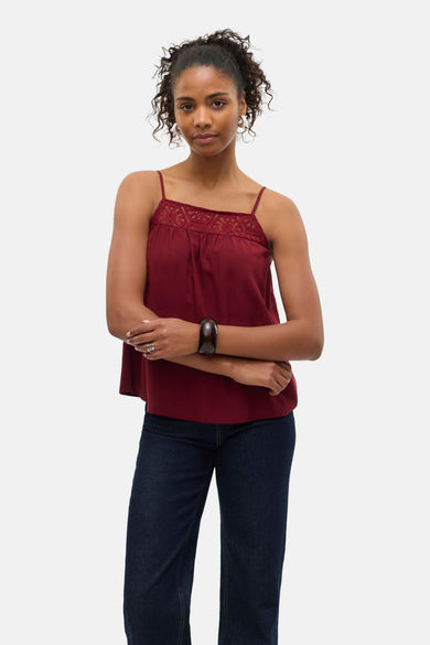 Mouwloze bordeaux blouse van Vero Moda, afgewerkt met kanten details aan de bovenkant, gecombineerd met donkere jeans en een armband.
