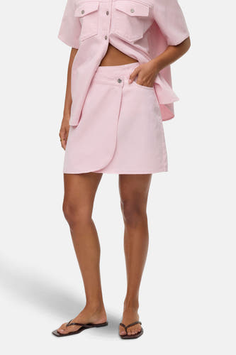 Roze korte rok van Vero Moda, met omslagdetail en steekzak, gecombineerd met een roze overhemd.