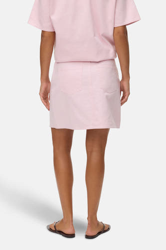Roze, korte rok van VERO MODA, gezien van achteren, gecombineerd met een roze shirt en bruine slippers.
