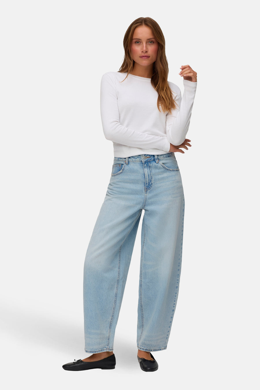 Lichtblauwe denim jeans van VERO MODA, met wijde pijpen, gecombineerd met een wit shirt en zwarte ballerina's.