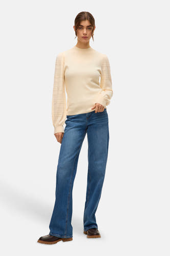 Veste écru avec col rond de VERO MODA, man manues longues à motif ajouré, associée à des jeans bleus et des chaussures marrons.