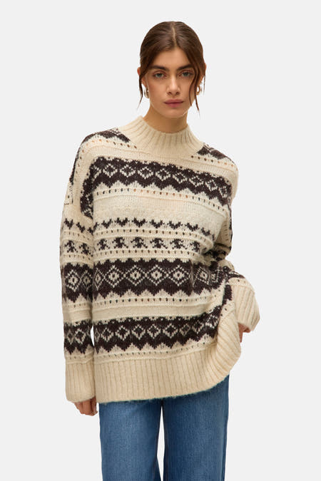 Ecrukleurige trui met ronde hals van VERO MODA met donkerbruin fair isle patroon en lange mouwen, gecombineerd met een blauwe jeans.
