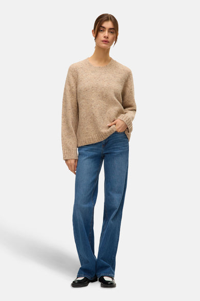 Beige trui met ronde hals van VERO MODA®, gecombineerd met een blauwe jeans en zwarte schoenen.