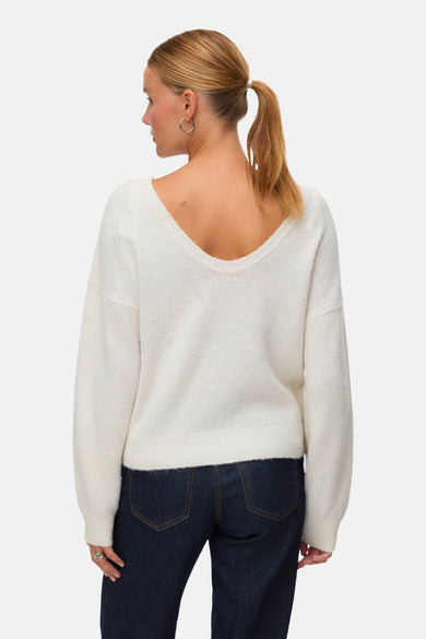 Gilet beige avec col rond de VERO MODA, porté en arrière avec des jeans foncés et des boucles d'oreilles argentées.
