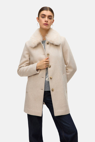 Gilet écru de VERO MODA avec col en fourrure, porté sur un pull gris et des jeans foncés.