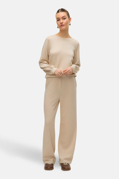 Ecru broek van VERO MODA, met wijde pijpen, gedragen met een bijpassende top en bruine schoenen.
