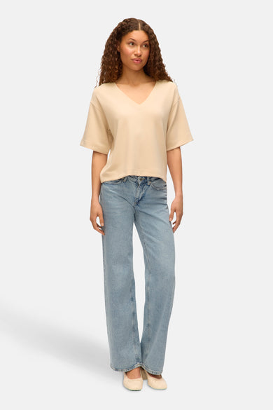 Ecru T-shirt met korte mouwen van VERO MODA, gedragen met wijde jeans en ballerina's.