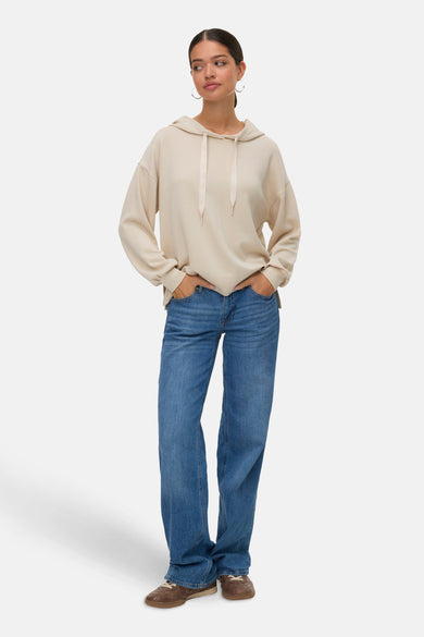 Ecrukleurige sweater met kap van VERO MODA, gedragen met blauwe jeans en bruine schoenen.