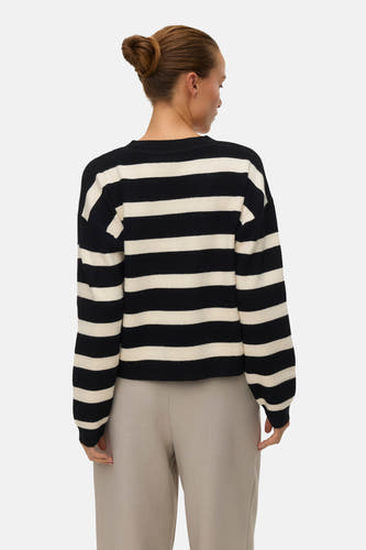 Cardigan rayé noir et blanc de VERO MODA, vu de dos, avec des manches longues et un pantalon beige.